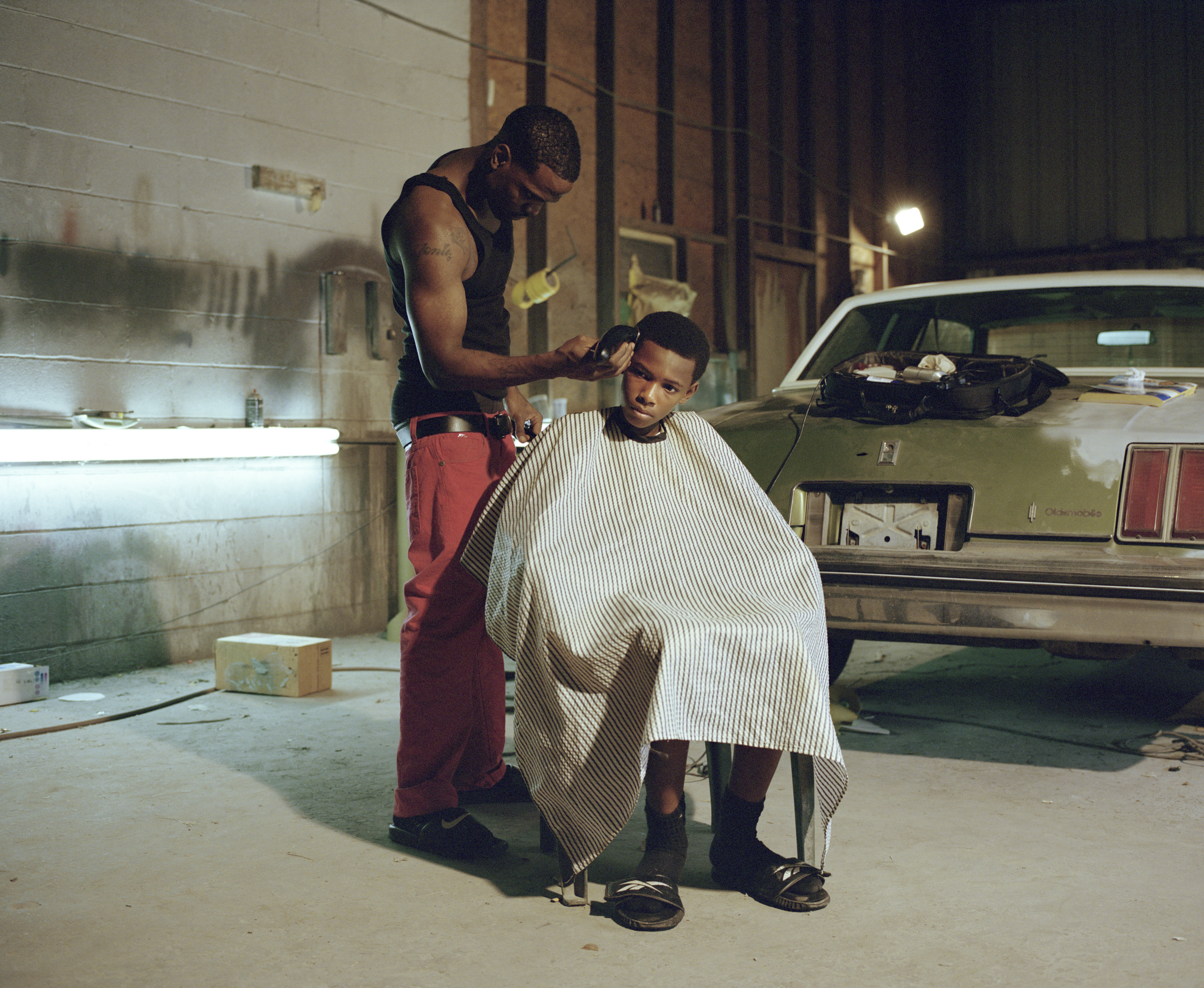 Blessing Montana is giving a haircut to his brother Satino Montana in the garage where they work. Baton Rouge, LA